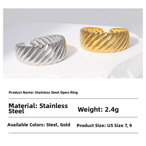 Detailed view of twisted croissant style stainless steel rings on a white stone pedestal