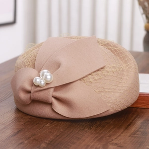 Detail of wool beret featuring a beige mesh veil, large bow and white pearl accents