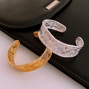 Detail shot of vintage gold mesh open cuff bracelet on elegant black leather bag