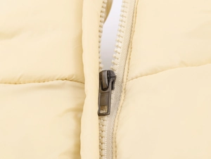 Detail of metal zipper and quilted fabric on yellow hooded winter coat for women