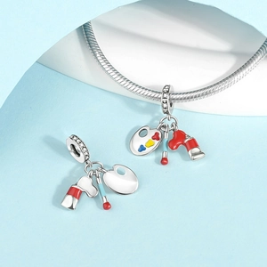 Silver artist palette charm with colorful enamel and paint brushes on blue background