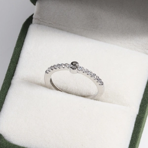 Macro shot of silver letter S ring with diamond accents in a green velvet jewelry box