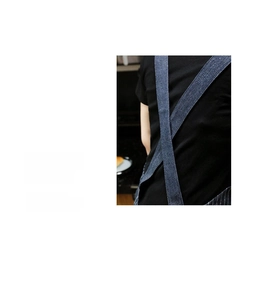 Detail of ergonomic cross-back shoulder straps on a navy blue denim work apron