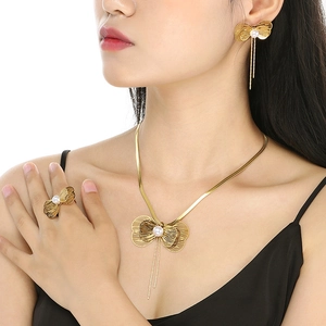 Model wearing a gold butterfly jewelry set with pearls, including necklace and earrings