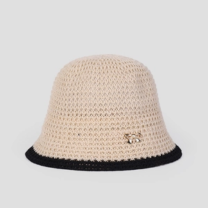 Detail of hollow knit sun hat with contrast weave and golden metal butterfly accent