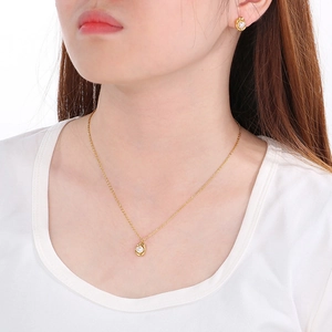 Close-up of golden shell and pearl necklace with matching earrings on female model