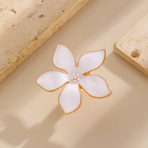 Détails d'une bague fleur dorée avec pétales en émail blanc et centre en perles