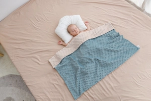 Dettaglio del morbido tessuto minky su una coperta calmante per neonati beige e blu verde