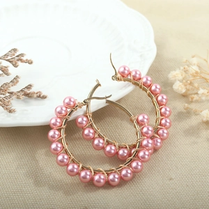 Close-up of handmade gold wire hoop earrings featuring delicate pink pearl beads