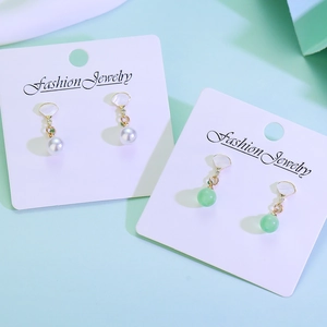 Detail of fan-shaped drop earrings with white shell inlay and green jade-style beads