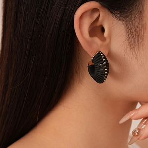 Detail of vintage black textured fan-shaped earrings with gold beads on ear