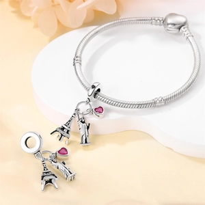Macro shot of silver charm bracelet featuring Eiffel Tower, Statue of Liberty and red heart
