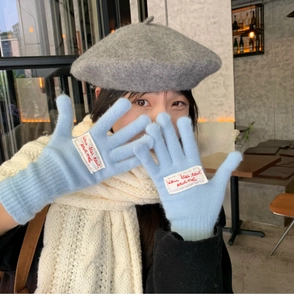 Detail of light blue knitted gloves with a chic French embroidery patch for winter