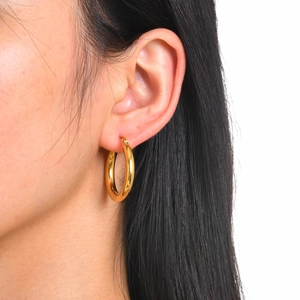 Close-up of polished 18k gold-plated stainless steel hoop earrings worn on ear