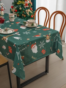 Detailed view of dark green Christmas tablecloth with Santa and reindeer motifs in a cozy room