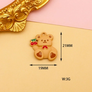 Detail view of a 21mm brown bear charm with a red bow and cherry on a pink background