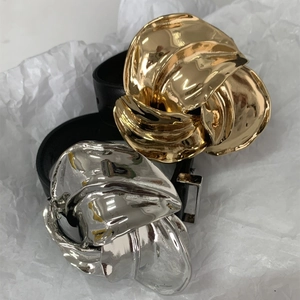 Detail van gouden en zilveren onregelmatige metalen gespen op zwarte lederen riemen
