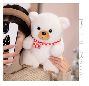 Close-up of cute white teddy bear plush toy with red and white checkered scarf detail