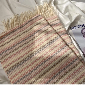 Detail of pink and beige checkered scarf fabric with soft fringes on silk background