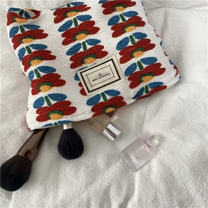 Detailed macro view of pleated floral makeup bag with Pleasant Time fabric label