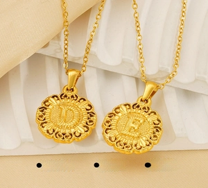 Detailed macro view of polished gold stainless steel alphabet pendants with letter D and E