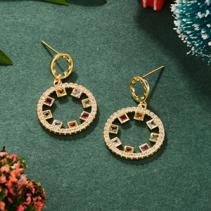 Close-up of gold round stud earrings with colorful zircon stones on green festive background