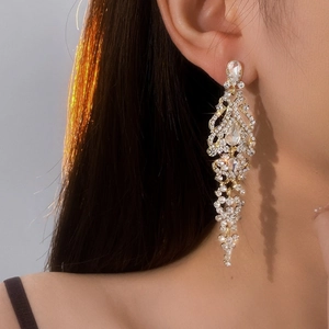 Close-up of gold tassel drop earrings with sparkling rhinestones worn by a model