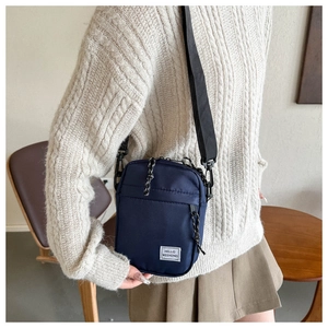 Detail of navy blue nylon crossbody bag with zipper pocket and Hello Weekend label
