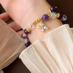 Close-up of a purple beaded bracelet with butterfly pendant on a soft fabric sleeve