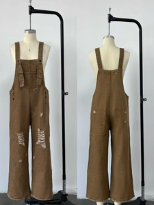 Detail of vintage brown denim overalls featuring distressed holes and side buttons