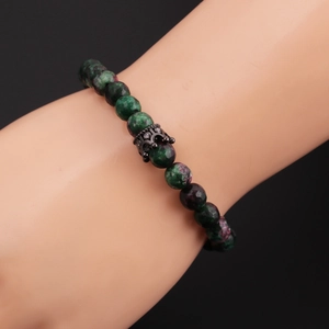 Close-up of 8mm green and purple stone beaded bracelet with a black crown charm on wrist