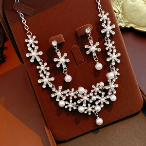 Detailed close-up of diamond flower and pearl jewelry set on brown velvet display