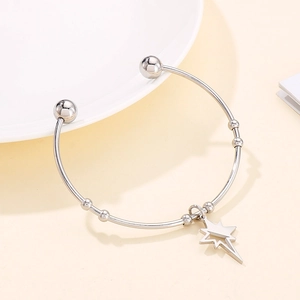 Detailed macro view of an open silver star bangle with polished finish and star charm