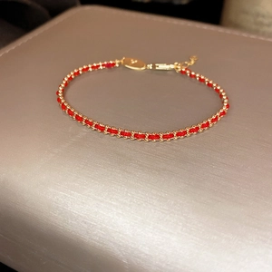 Detail of red braided bracelet with gold plated beads and adjustable lobster clasp