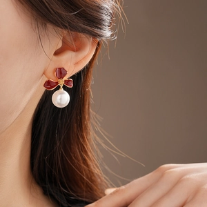 Detail of red flower pearl earrings featuring vintage French style on a female model