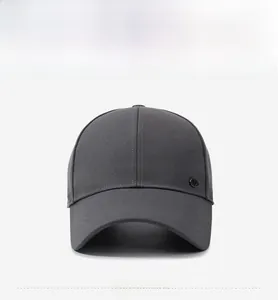Detail of dark gray cotton baseball cap with circular metal logo and curved brim