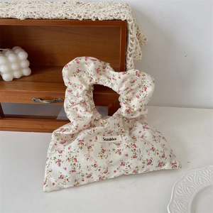 Detail of floral canvas wristlet bag with ruffled handle and vintage pastoral patterns