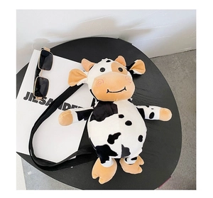 Detail shot of plush cow crossbody bag with black adjustable strap and soft cowhide pattern
