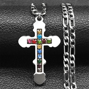 Close-up of silver cross pendant with multi-colored rhinestones on a Figaro chain necklace