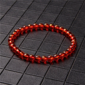 Detailed shot of 6mm red agate beads featuring golden engraved Sanskrit mantras on a bracelet