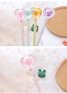 Close-up of cute heart-shaped crystal pens in pastel colors on a rustic wooden tray