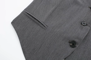 Détail macro du tissu en sergé gris et des boutons noirs sur un gilet de costume