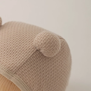 Baby knit earflap hat with double pom-poms and waffle texture in beige color
