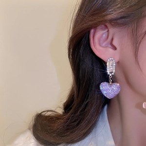 Close-up of sparkling purple heart drop earring with cubic zirconia on model