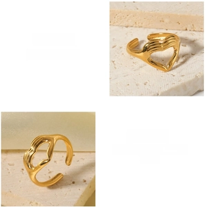 Detail view of gold heart ring featuring hands embracing heart design with polished finish