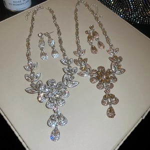 Detailed flat lay of floral necklace and earring sets with pear-shaped rhinestones