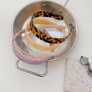 Flat lay of acetate hairbands in tortoiseshell and marble patterns inside a metal bowl