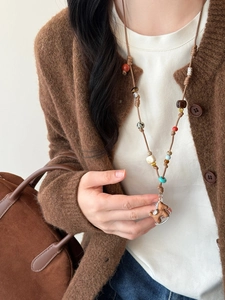 Detail of beaded necklace with horse pendant and braided cord on a model