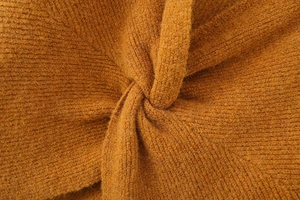 Close-up detail of ginger yellow knit sweater showing chunky textured fabric and back knot tie