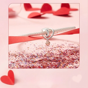 Close-up of heart-shaped tassel beads in silver and rose gold on a mesh bracelet